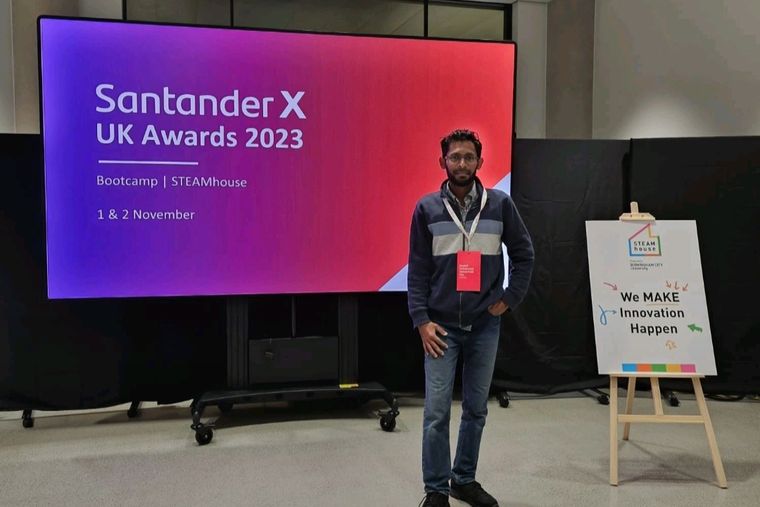 Standing in front of the Santander X UK Awards 2023 bootcamp screen at STEAMhouse, Birmingham City University.